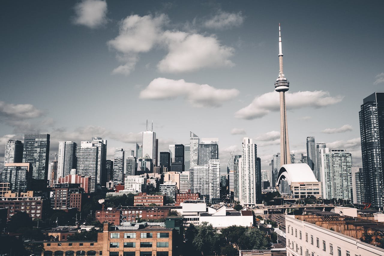 hero-img-02 Stunning Toronto skyline with the iconic CN Tower under a cloudy sky, showcasing urban architecture.