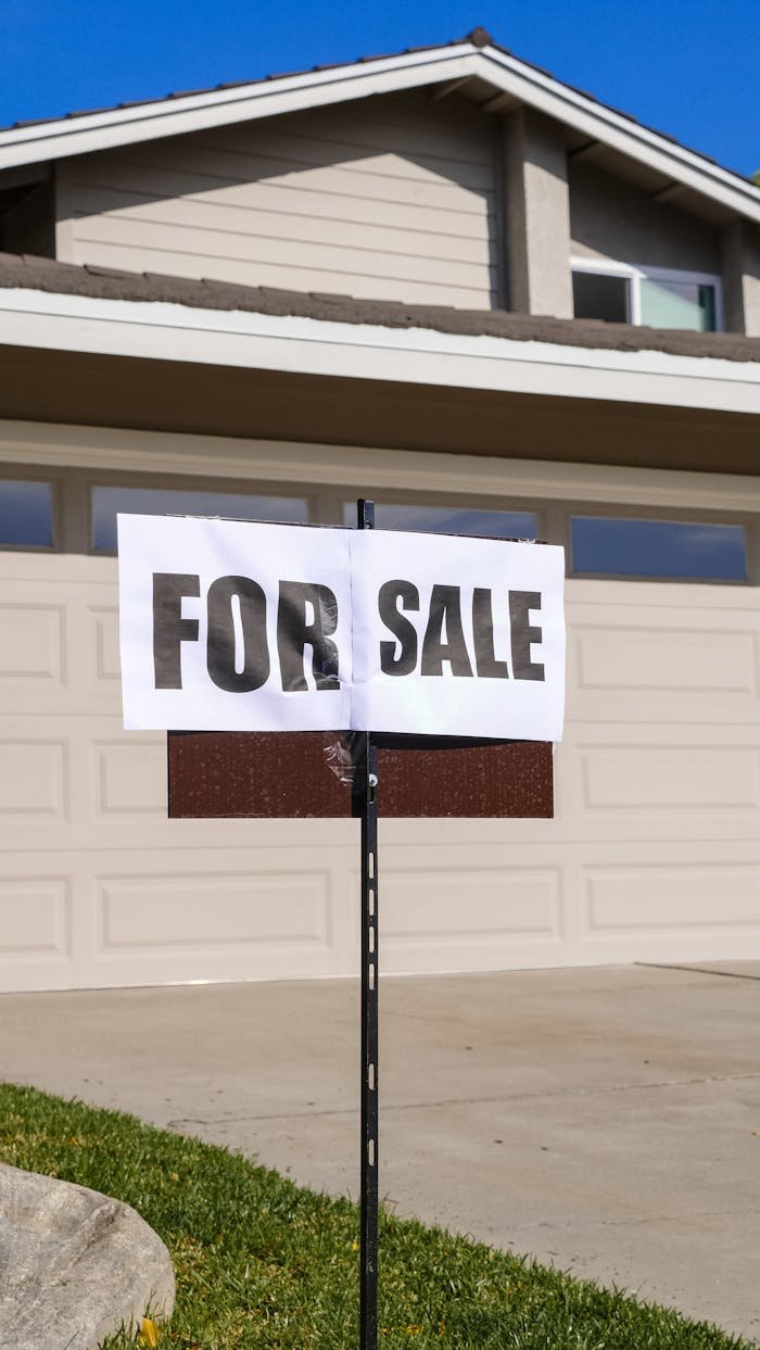 gallery-4 A modern suburban house with a prominent For Sale sign in the front yard, ideal for real estate listings.