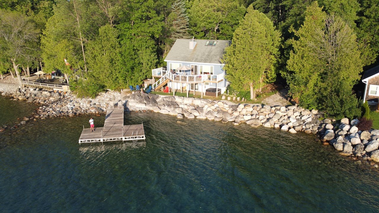 Picturesque lakeside house with a wooden dock on a sunny day in Meaford, Ontario.